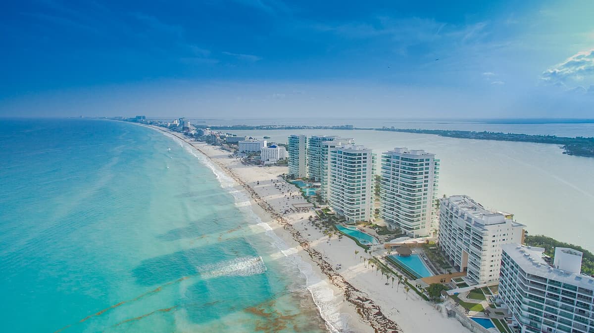 Vista aérea de hoteles de lujo en la zona hotelera de Cancún con playa y mar turqueso.