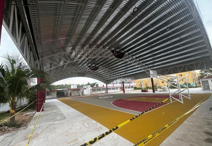 Cancha de basquetbol techada con estructura metálica de acero galvanizado en construcción, ubicada bajo un amplio domos con vigas aparentes.