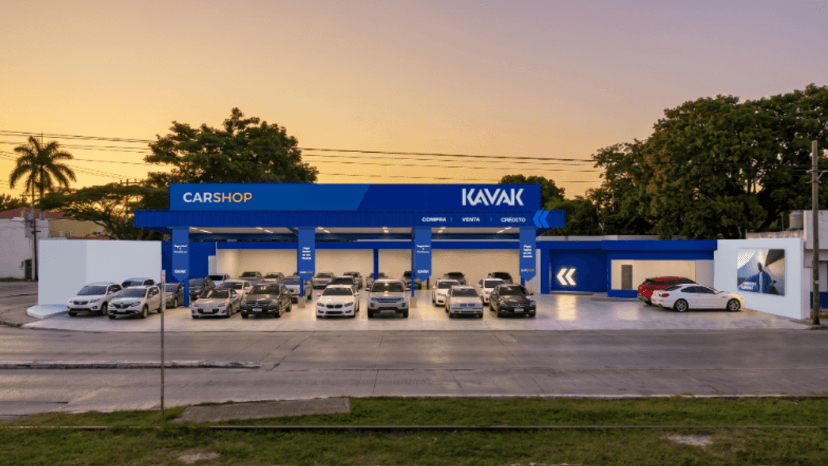 Showroom Kavak con fachada azul y blanca exhibiendo múltiples vehículos en el piso de ventas al atardecer.